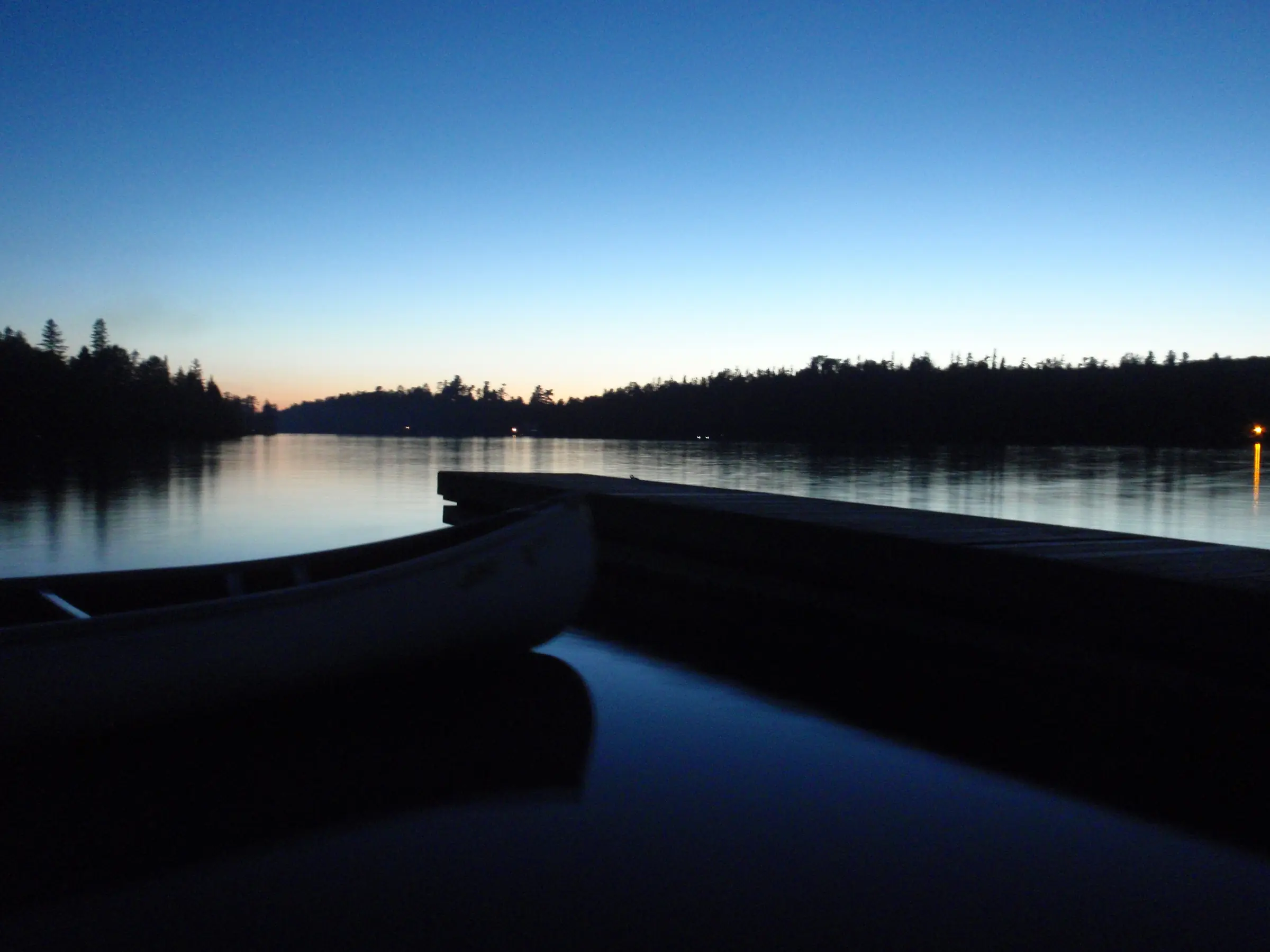 A still lake at dusk in Temagami, with a dark treeline under a deep blue sky